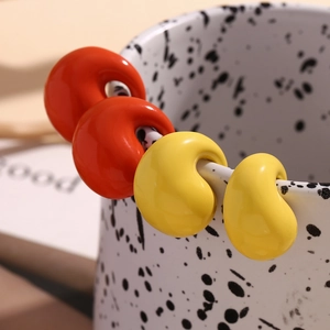 Detailed macro view of orange and yellow C-shaped earrings on a ceramic cup rim