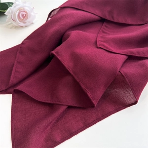 Detailed view of dark red cotton linen scarf texture with soft folds and elegant white rose