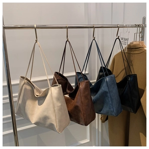 Minimalist large tote bags shown in cream, caramel, navy and black displayed on a rack
