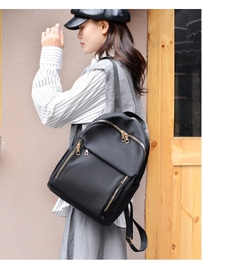 Side view of a black nylon backpack for women with gold zippers shown on a model