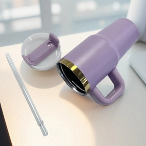 Detail view of purple stainless steel tumbler with handle, golden rim and straw