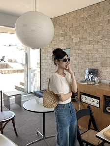 Chic lifestyle scene featuring a khaki hollow woven bucket bag with blue denim jeans