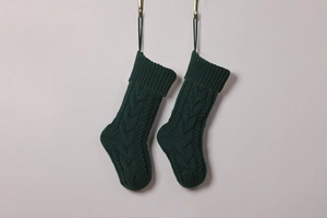 Detail of dark green cable knit Christmas stockings with textured patterns and hanging loops