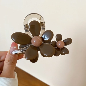 Dettaglio ravvicinato della pinza per capelli a fiori in resina marrone e beige