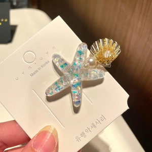 Detail of starfish and shell hair clips with glitter and pearls on display card