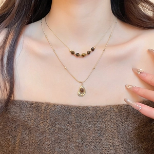 Detail of layered gold necklaces with tiger eye beads and an oval vintage pendant