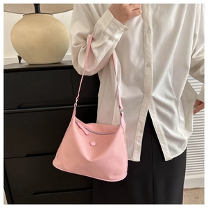 Detail of a pink nylon tote bag showing the snap button pocket and zipper closure