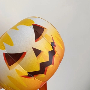 Close-up of a pumpkin-shaped round crossbody bag featuring a classic spooky jack-o-lantern face