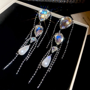 Detail of silver drop earrings with crystal tassels and white pearls on black velvet