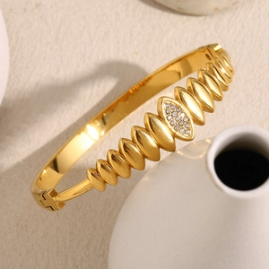 Polished 18K gold plated bangle with water drop zircon pattern on a ceramic vase