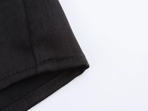 Detail view of double-stitched hem and woven fabric texture on a black long sleeve shirt
