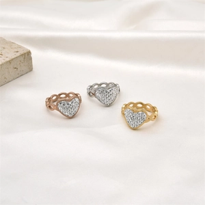 Détail de trois bagues en forme de cœur évidé en or rose, argent et or sur soie blanche