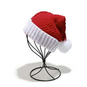 Classic red and white knitted Christmas hat with a fluffy pompom on a black metal stand