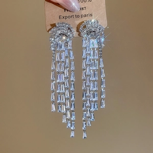 Vue détaillée des pompons en zircone baguette en cascade sur des boucles d'oreilles
