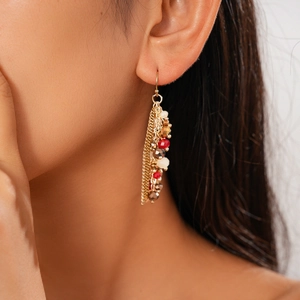 Detail view of long tassel earrings with stone beads and golden chains on model