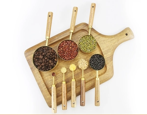 Flat lay of 8-piece stainless steel measuring set with acacia wood handles on board