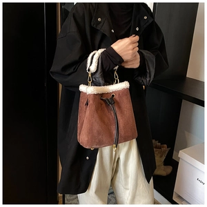 Close-up of brown suede bucket bag with white faux fur trim and gold metal hardware detail