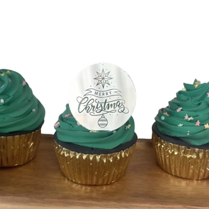 Close-up of Merry Christmas acrylic cupcake topper on festive green frosted cake