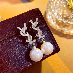 Gros plan de boucles d'oreilles cœur en perles dorées avec zircon sur texture cuir