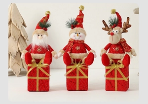 Detail of Santa, snowman, and reindeer plush dolls sitting on red gift boxes