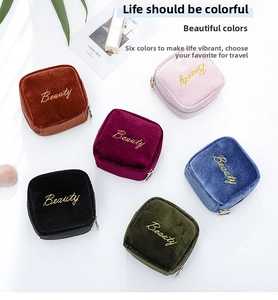 Detailed flat lay of velvet cosmetic pouches in six colors with gold Beauty embroidery