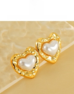 Detail of heart stud earrings featuring hammered gold texture and pearl center inlay