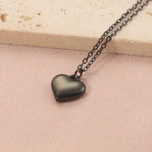 Détail d'un collier pendentif cœur noir minimaliste sur soie et pierre