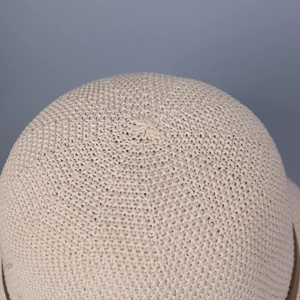 Macro shot of tight crochet pattern on crown of beige knit sun hat with detailed texture