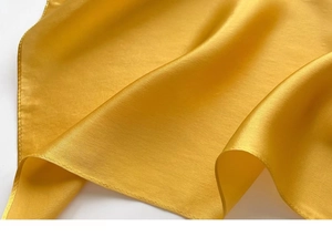 Detailed view of smooth silk-like texture and sheen on a golden square scarf