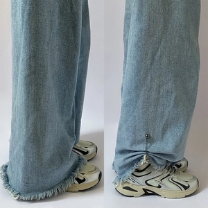 Detail showing magnetic chain clip shortening denim jeans hem with frayed edges effect
