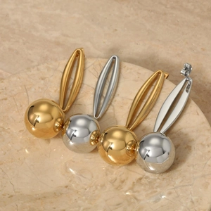 Polished hollow sphere earrings in gold and silver finish on a marble surface