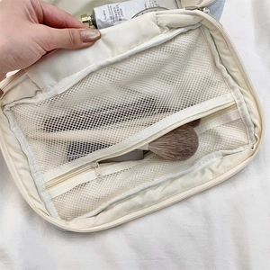 Close-up of quilted makeup bag interior featuring double mesh zipper pockets for storage