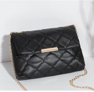 Close-up of black quilted shoulder bag featuring gold chain and rectangular metal clasp