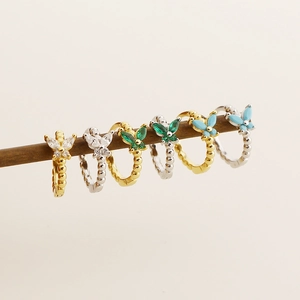 Detail view of butterfly hoop earrings in gold and silver with colorful zircon accents