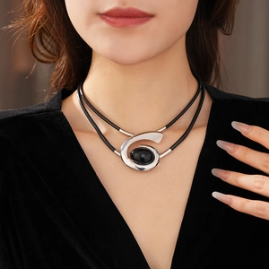 Close-up of double-layer black leather necklace with oval gemstone spiral pendant