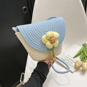 Detail of handmade woven shell bag with large floral decoration and blue rope strap