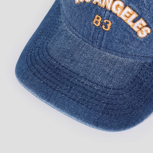 Close-up of Los Angeles letter embroidery on washed blue denim baseball cap