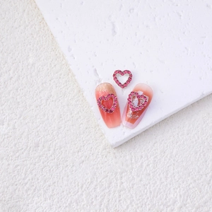 Detail of rose red hollow heart nail charms with rhinestones on pink glitter nails