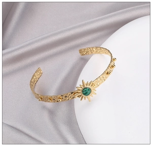 Detail of gold-plated hammered cuff bracelet featuring a green malachite sunburst motif