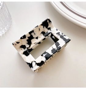 Detail of a rectangular marble pattern acetate hair claw clip on a clean white surface