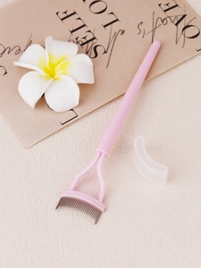 Close-up of curved steel tooth eyelash comb with pink handle and clear protective cap