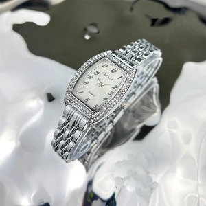 Close-up of silver tonneau quartz watch with rhinestone bezel on satin-like fluid fabric