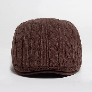 Detailed knit texture of dark brown winter beret hat with vintage cable stitch patterns
