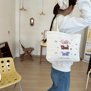 Detail of white quilted handbag featuring cute cat embroidery and soft padded texture