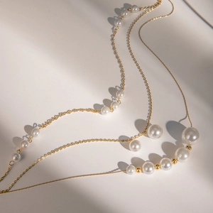 Detailed view of 18k gold stainless steel necklace with white pearls on a minimalist background