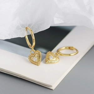Detailed view of gold heart earrings with sunburst texture and small zircon stone