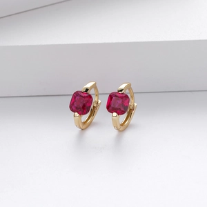 Macro shot of gold hoop earrings featuring square-cut red zircon stones on a clean background
