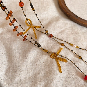 Detailed view of handmade beaded dragonfly necklace with amber and red beads