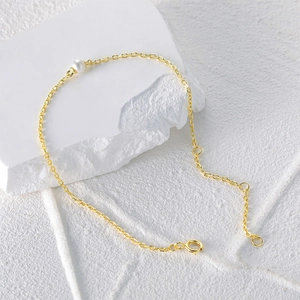 Detail of a 925 silver gold-plated pearl bracelet on a minimalist stone background
