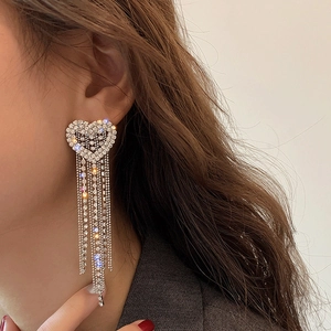 Detail view of silver tassel earrings with heart-shaped rhinestones on a model